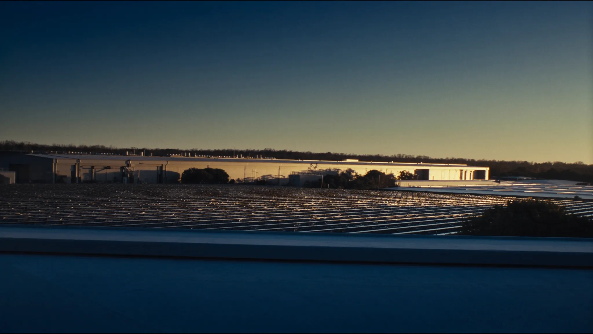 A commercial solar array in front of a Midwestern industrial manufacturing facility at dusk: federal ITC safe harbor planning before the July 4, 2026 deadline